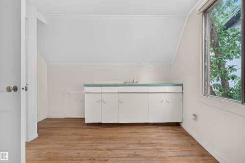 Wood-finish flooring, built-in cabinetry with a countertop and sink, and a window providing natural illumination - 9026 92 Street Nw, Edmonton, AB - Indoor Photo Showing Other Room