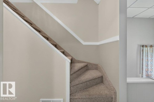 Carpeted staircase with white trim, neutral wall paint, and white crown molding - 9026 92 Street Nw, Edmonton, AB - Indoor Photo Showing Other Room