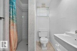 Tiled shower stall, white pedestal sink, and white toilet - 