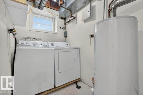 Dedicated laundry area featuring a white washing machine and dryer, a water heater, and a window - 9026 92 Street Nw, Edmonton, AB - Indoor Photo Showing Laundry Room