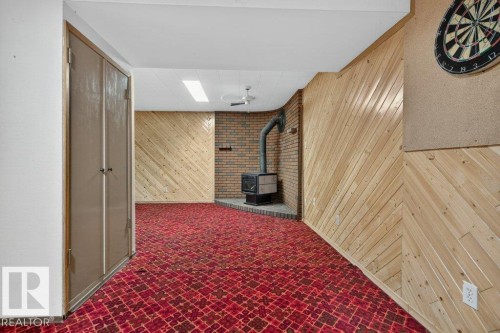 Wood-paneled walls, brick accent wall, built-in wood-burning stove, and overhead ceiling fan - 9026 92 Street Nw, Edmonton, AB - Indoor Photo Showing Other Room With Fireplace