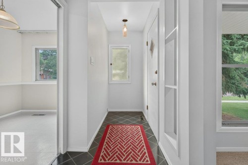 Entryway featuring diamond-patterned floor tiles, a window with obscure glass, and a paneled entry door with a diamond-shaped glass insert - 9026 92 Street Nw, Edmonton, AB - Indoor Photo Showing Other Room
