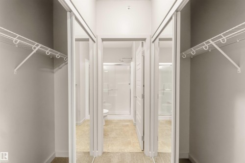 Sliding mirrored doors, white wire shelving, light-toned flooring, and a shower enclosure - #414 5510 Schonsee Dr Nw, Edmonton, AB - Indoor With Storage