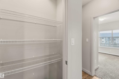 Closet featuring multiple wire shelving units, light gray wall paint, and a wood-finish flooring threshold - #414 5510 Schonsee Dr Nw, Edmonton, AB - Indoor With Storage