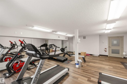 Fitness area featuring wood-finish flooring, mirrored wall, and recessed lighting - #414 5510 Schonsee Dr Nw, Edmonton, AB - Indoor Photo Showing Gym Room