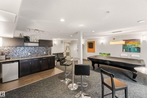 Integrated wet bar with mosaic tile backsplash, dark wood cabinetry, and a built-in beverage refrigerator - #414 5510 Schonsee Dr Nw, Edmonton, AB - Indoor