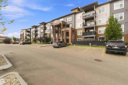 Contemporary multi-story building featuring brick and panel siding, private balconies, and a designated parking area - #414 5510 Schonsee Dr Nw, Edmonton, AB - Outdoor With Facade