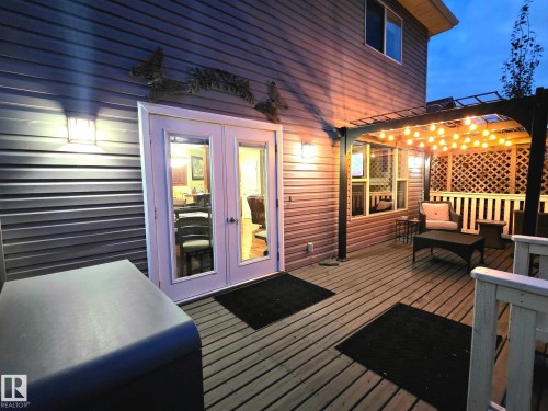 Exterior wood-finish deck with a pergola, lattice screening, and dual French doors - 9606 82 Avenue, Morinville, AB 