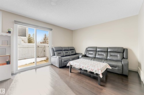 Wood-finish flooring, light-toned walls, and a sliding glass patio door - #37 1411 Mill Woods Rd E Nw, Edmonton, AB - Indoor Photo Showing Living Room