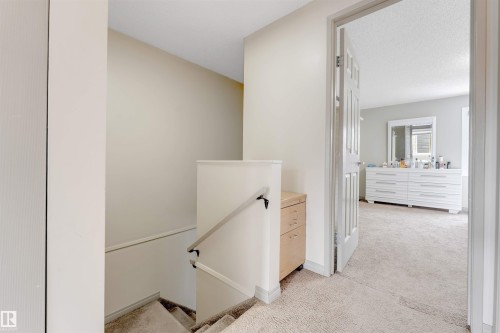 Carpeted flooring extending through a doorway, with a wood-finish cabinet built into the wall - #37 1411 Mill Woods Rd E Nw, Edmonton, AB - Indoor Photo Showing Other Room
