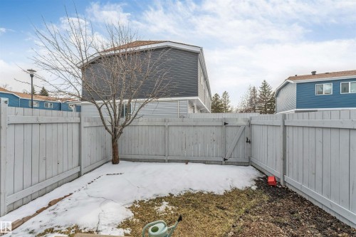 Fenced backyard with a wooden gate, mature tree, and partial grass coverage - #37 1411 Mill Woods Rd E Nw, Edmonton, AB - Outdoor