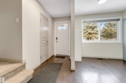 Entryway featuring a white paneled door, dark wood-finish flooring, and a large window - 
