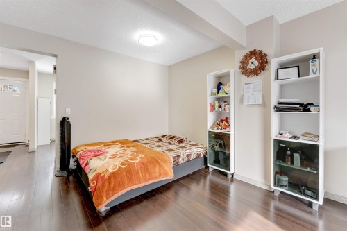 Wood-finish flooring throughout, light neutral wall paint, and a white interior door with decorative glass - #37 1411 Mill Woods Rd E Nw, Edmonton, AB - Indoor Photo Showing Bedroom