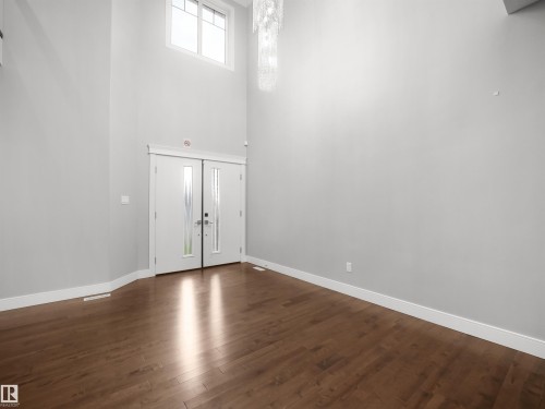 Double entry doors with frosted glass panels, wood-finish flooring, high ceilings, and a decorative light fixture - 17020 62 Street Nw, Edmonton, AB - Indoor Photo Showing Other Room
