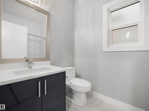 Modern vanity with dark cabinetry, integrated sink, and chrome faucet - 17020 62 Street Nw, Edmonton, AB - Indoor Photo Showing Bathroom