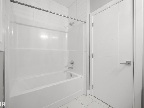 Tub and shower combination with chrome fixtures, subway tile surround, and a modern paneled door - 17020 62 Street Nw, Edmonton, AB - Indoor Photo Showing Bathroom