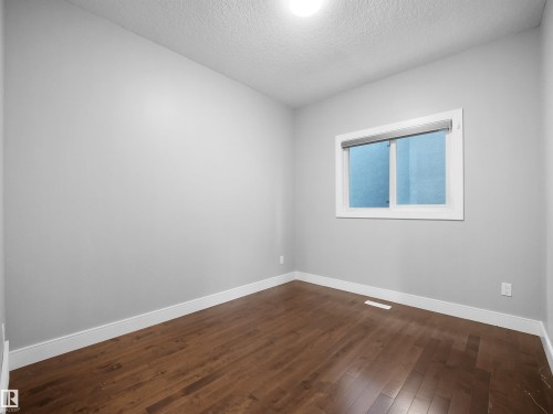 Wood-finish flooring with white trim, a single window with blinds, and recessed ceiling lighting - 17020 62 Street Nw, Edmonton, AB - Indoor Photo Showing Other Room