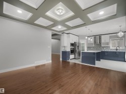 Hardwood-finish flooring extending into the kitchen with a coffered ceiling and recessed lighting - 