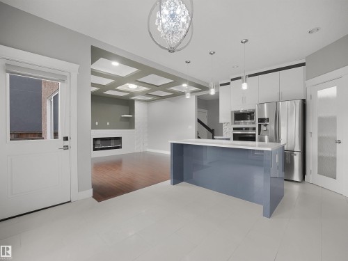 Kitchen island with a light blue finish and white countertop, stainless steel appliances, pendant lighting, wood-finish flooring, and a coffered ceiling - 17020 62 Street Nw, Edmonton, AB - Indoor Photo Showing Kitchen