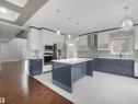 Contemporary kitchen featuring a large central island, stainless steel appliances, a patterned tile backsplash, white tile flooring, and contrasting blue and white cabinetry - 17020 62 Street Nw, Edmonton, AB  - Indoor Photo Showing Kitchen With Upgraded Kitchen 