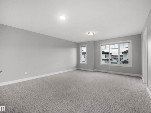 Spacious room with light gray walls, textured gray carpeting, multiple windows, and recessed lighting - 17020 62 Street Nw, Edmonton, AB - Indoor