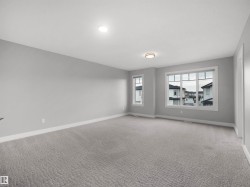 Spacious room with light gray walls, textured gray carpeting, multiple windows, and recessed lighting - 