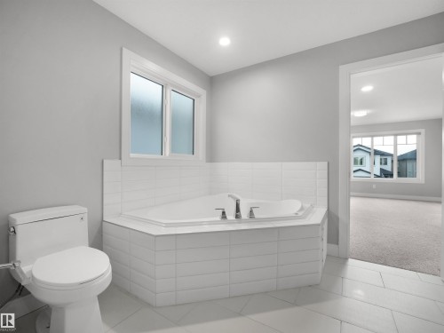 Corner soaking tub with tile surround, white toilet, and recessed lighting - 17020 62 Street Nw, Edmonton, AB - Indoor Photo Showing Bathroom
