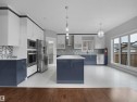 Open-concept kitchen with a central island, stainless steel appliances, large sliding glass doors, and two-tone cabinetry - 17020 62 Street Nw, Edmonton, AB  - Indoor Photo Showing Kitchen With Upgraded Kitchen 