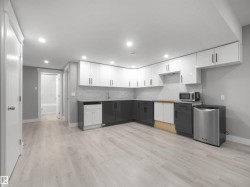 Corner kitchen with two-tone cabinetry, mosaic tile backsplash, and light wood-finish flooring - 