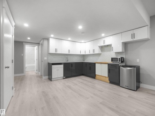 Modern kitchen area featuring two-tone cabinetry, wood-finish flooring, and recessed ceiling lighting - 17020 62 Street Nw, Edmonton, AB - Indoor Photo Showing Kitchen