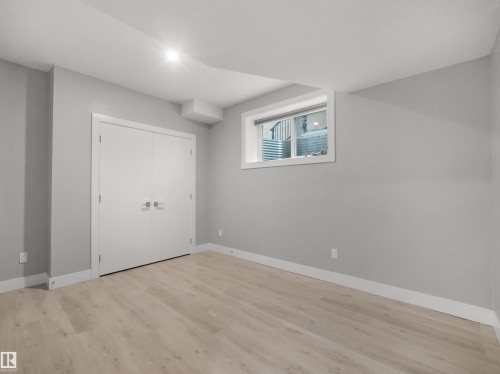 Light wood-finish flooring, white trim, and a white window frame complement the neutral wall tones - 17020 62 Street Nw, Edmonton, AB - Indoor Photo Showing Other Room