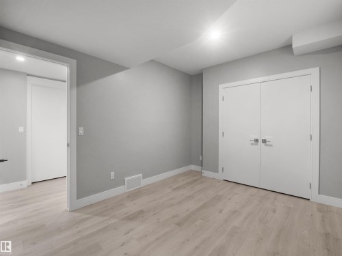 Light wood-finish flooring with white trim, gray painted walls, and white bi-fold doors - 17020 62 Street Nw, Edmonton, AB - Indoor Photo Showing Other Room
