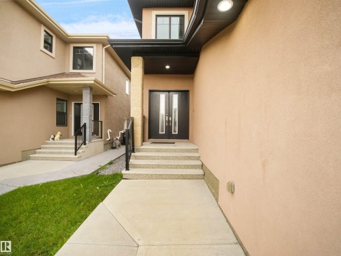 Stucco exterior with concrete walkways, black double entry doors, and overhead recessed lighting - 17020 62 Street Nw, Edmonton, AB - Outdoor