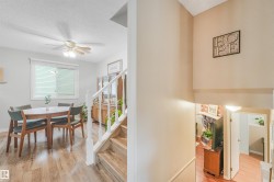 Open-concept dining area featuring wood-finish flooring, a ceiling fan with light fixture, and a window with blinds - 