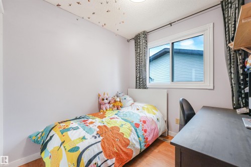 Light-filled room featuring wood-finish flooring, a white-framed window, and a ceiling light fixture - 18611 57 Avenue Nw, Edmonton, AB - Indoor Photo Showing Bedroom