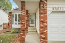 Exterior featuring brick columns, bay windows, white siding, and a white garage door - 18611 57 Avenue Nw, Edmonton, AB  - Outdoor 