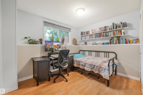 Interior room featuring wood-finish flooring and a window with a roller shade - 18611 57 Avenue Nw, Edmonton, AB - Indoor Photo Showing Bedroom
