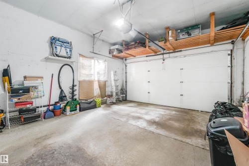 Single-car garage featuring a white overhead door, concrete flooring, and overhead wood slat storage shelving - 18611 57 Avenue Nw, Edmonton, AB - Indoor Photo Showing Garage