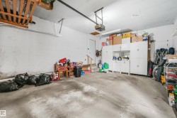 Spacious garage featuring concrete flooring, built-in white cabinetry, overhead storage, and a garage door opener - 