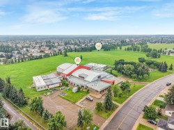 Spacious commercial building featuring a large parking lot, expansive green spaces, and a surrounding residential area - 