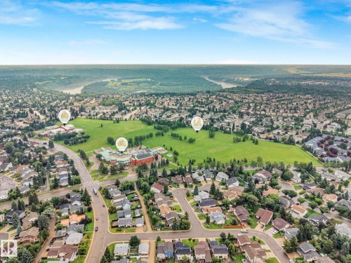 Aerial perspective showcasing a residential neighborhood with verdant green spaces, a winding river in the distance, and established community buildings - 18611 57 Avenue Nw, Edmonton, AB - Outdoor With View