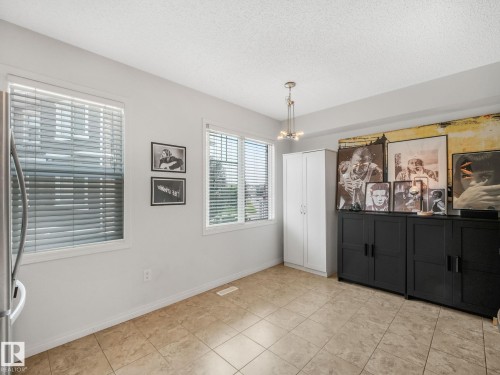 Spacious room featuring neutral-toned tile flooring, white walls, and multiple windows with blinds - #21 1140 Chappelle Bv Sw, Edmonton, AB - Indoor Photo Showing Other Room