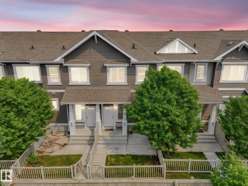 Multi-unit residential property featuring dark gray siding, white trim, and a shingled roof - #21 1140 Chappelle Bv Sw, Edmonton, AB - Outdoor With Facade
