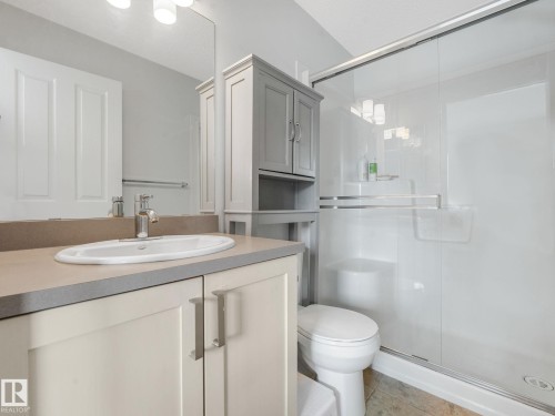 Bathroom featuring a vanity with an undermount sink, a countertop with a backsplash, a mirrored wall, and a separate shower enclosure with a sliding glass door - #21 1140 Chappelle Bv Sw, Edmonton, AB - Indoor Photo Showing Bathroom