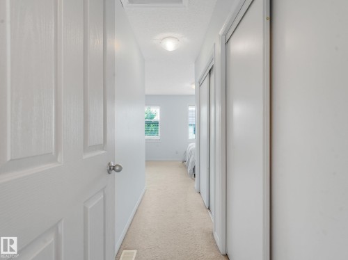 Hallway featuring light-colored carpet flooring, white walls, and a flush-mount ceiling light - #21 1140 Chappelle Bv Sw, Edmonton, AB - Indoor Photo Showing Other Room