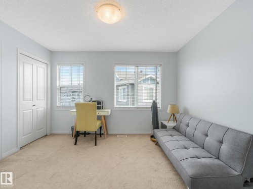 Carpeted room featuring two windows with blinds, a double-door closet, and a ceiling-mounted light fixture - #21 1140 Chappelle Bv Sw, Edmonton, AB - Indoor Photo Showing Office