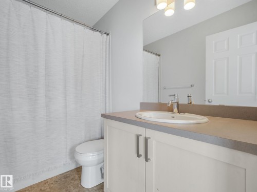Bathroom featuring a vanity with a light-colored countertop, an undermount sink, and chrome fixtures - #21 1140 Chappelle Bv Sw, Edmonton, AB - Indoor Photo Showing Bathroom