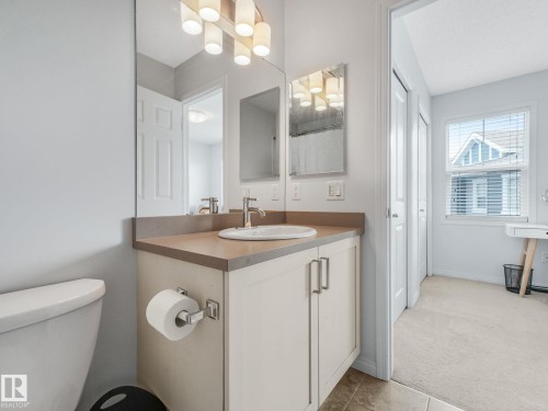 Bathroom featuring a single vanity with an undermount sink, a neutral countertop, and a contemporary light fixture - #21 1140 Chappelle Bv Sw, Edmonton, AB - Indoor Photo Showing Bathroom
