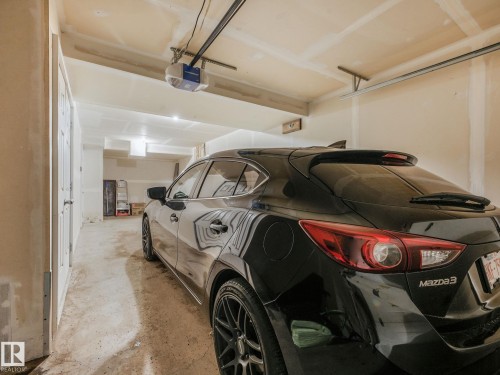 Spacious garage featuring a concrete floor, overhead lighting, and an automatic garage door opener system - #21 1140 Chappelle Bv Sw, Edmonton, AB - Indoor Photo Showing Garage