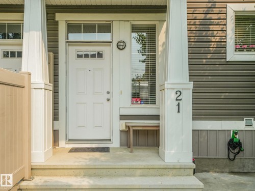 Inviting front entry featuring a white paneled door with transom windows, concrete steps, and a white architectural column - #21 1140 Chappelle Bv Sw, Edmonton, AB - Outdoor With Exterior